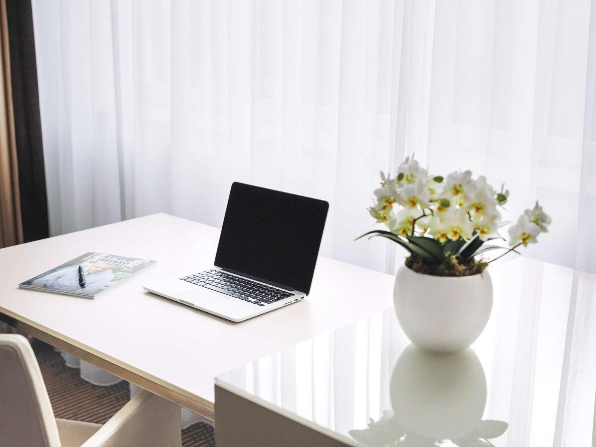 Pullman Berlin Schweizerhof Hotel Exterior photo A desk with a laptop and a vase of flowers